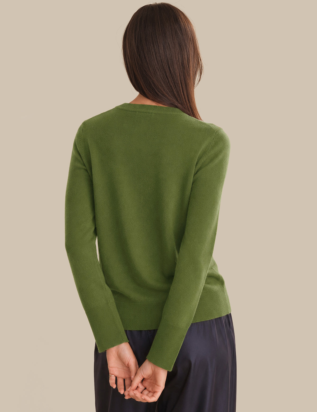 Person wearing a green sweater against a beige background
