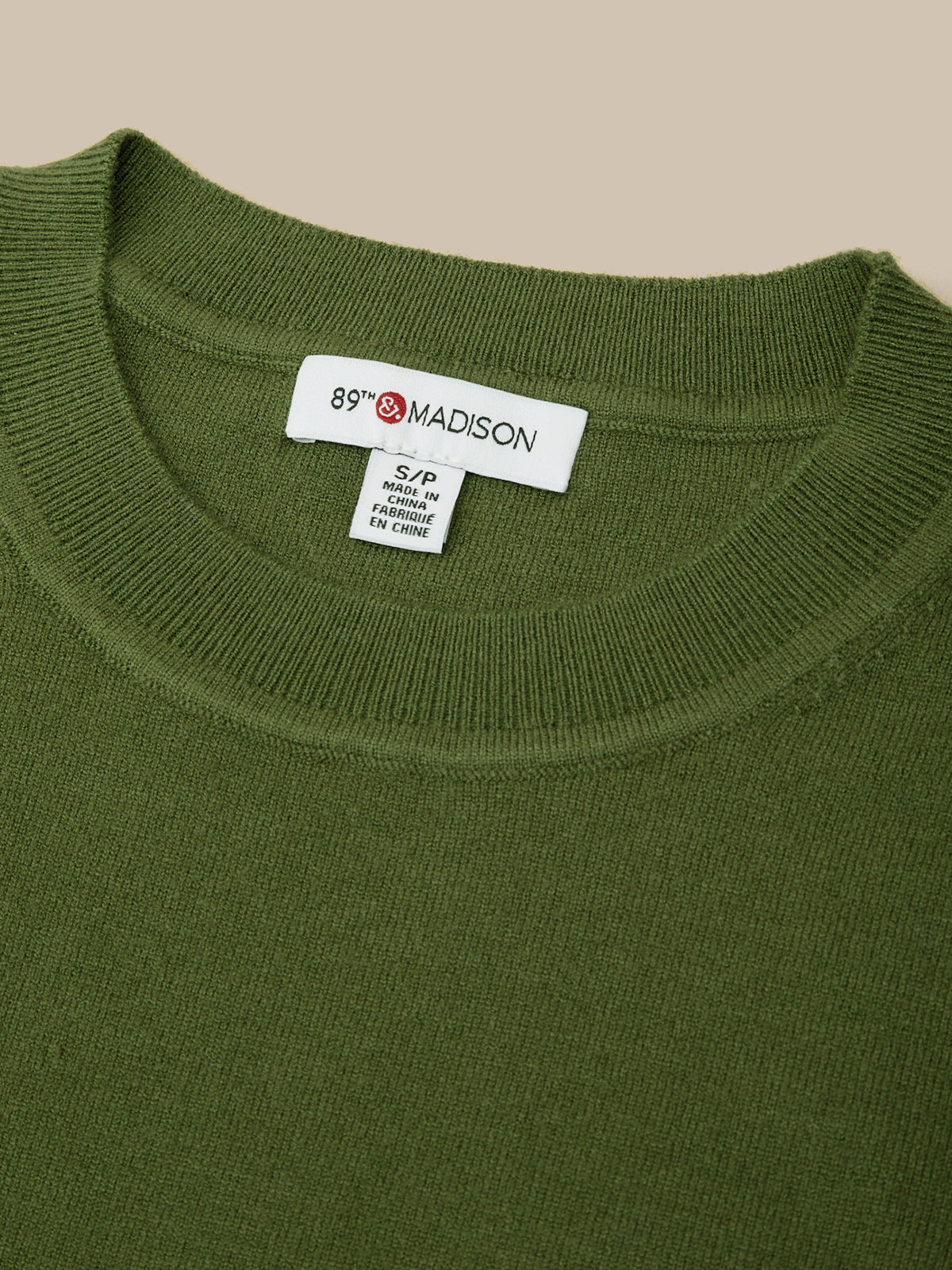 Green sweater with a brand label on the collar