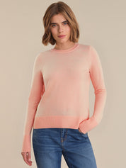 Woman wearing a pink sweater and blue jeans on a beige background