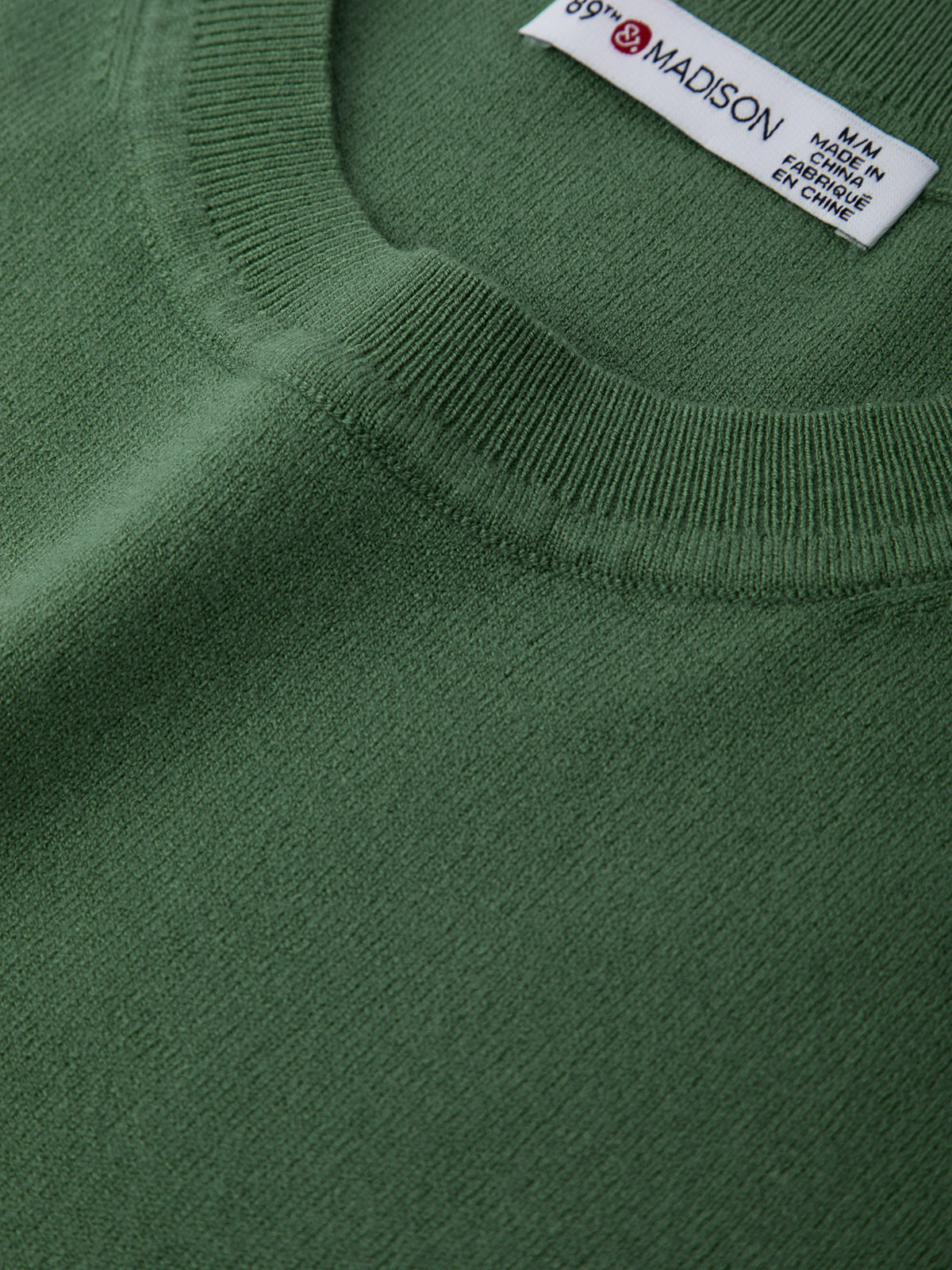 Close-up of a green sweater with a brand label on the collar.