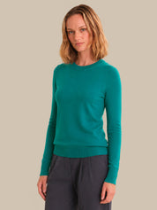 Woman wearing a teal sweater against a beige background