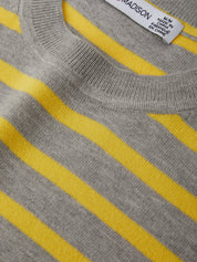 Close-up of a gray sweater with yellow stripes and a visible label.