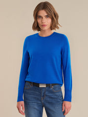 Woman wearing a blue sweater and jeans on a beige background