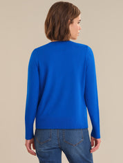 Person wearing a blue sweater and jeans against a beige background