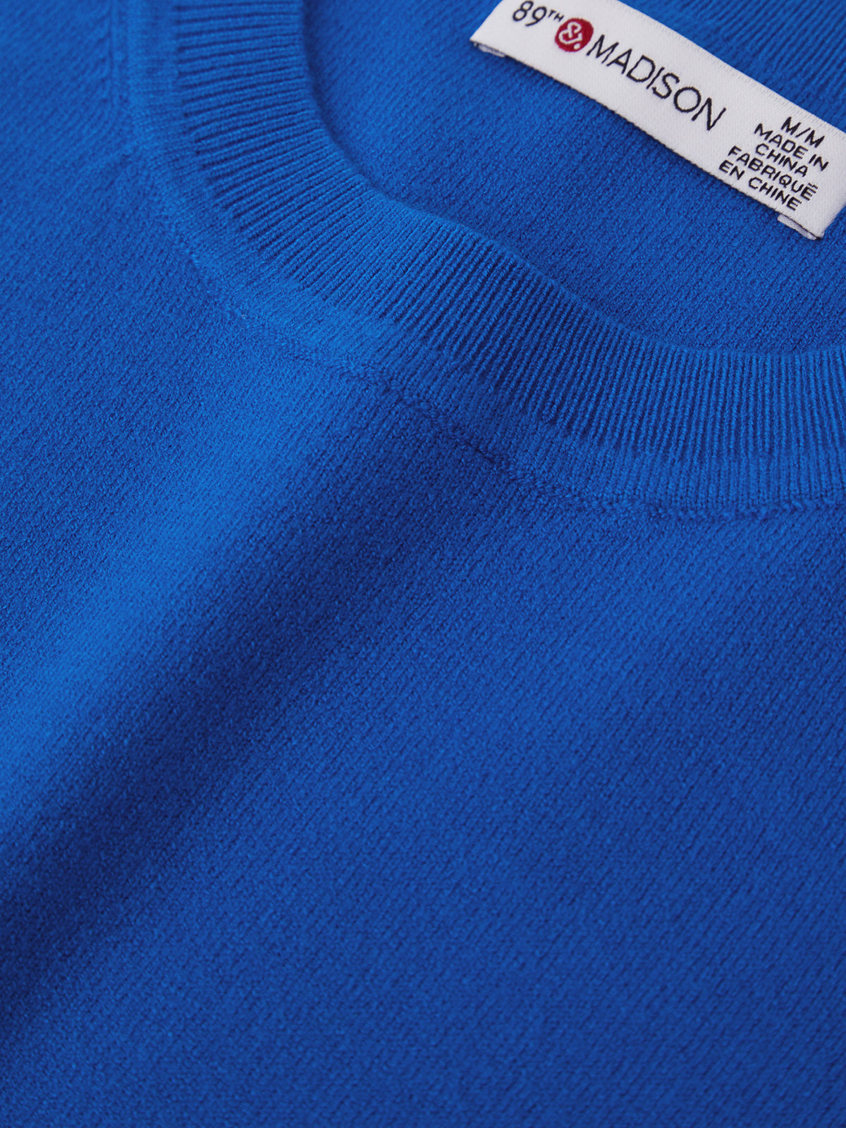 Close-up of a blue sweater with a brand label on the collar.