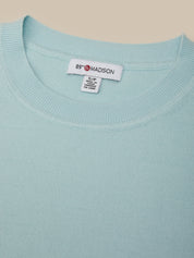 Light blue sweater with a brand label on a beige background