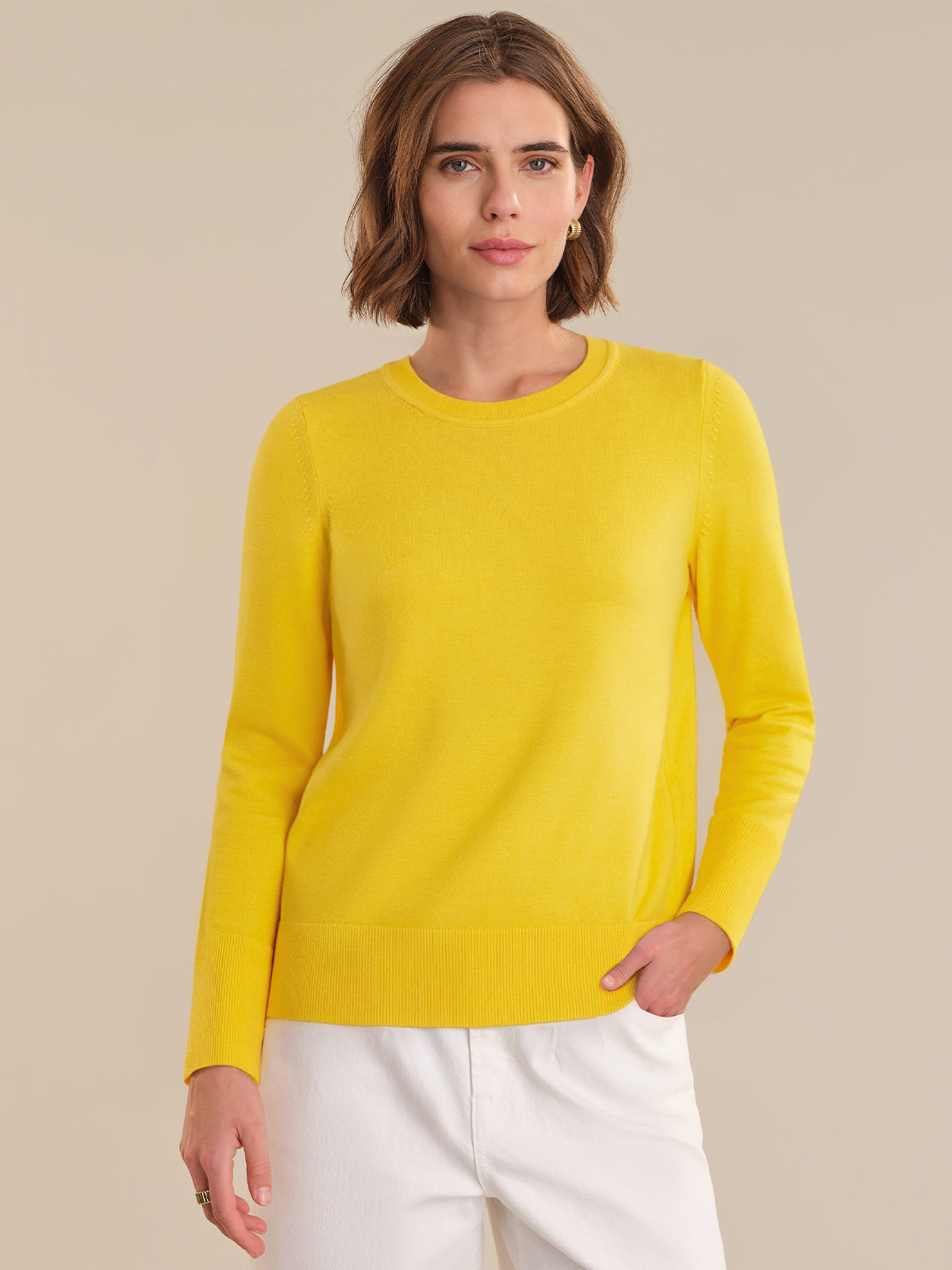 Woman wearing a yellow sweater against a beige background