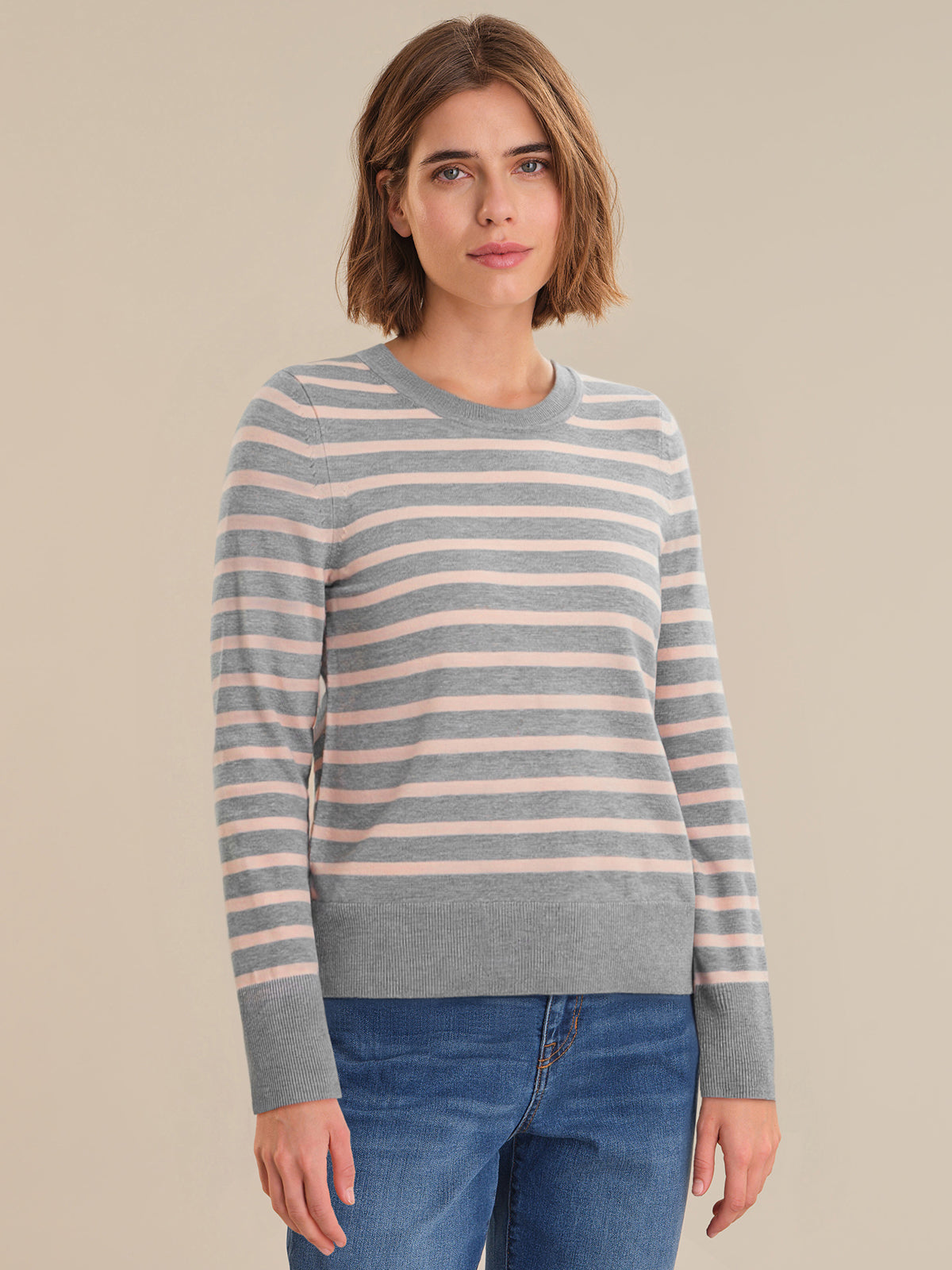 Woman wearing a striped sweater and jeans on a beige background