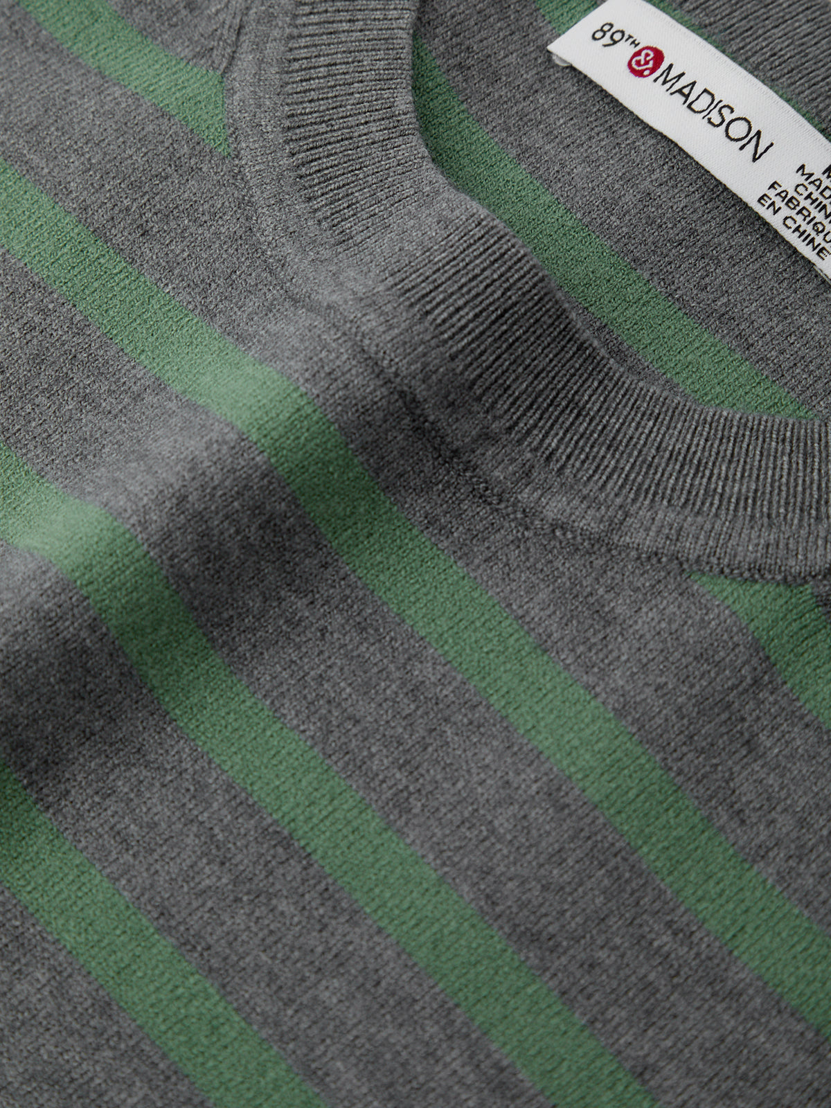 Close-up of a gray and green striped sweater with a brand label.