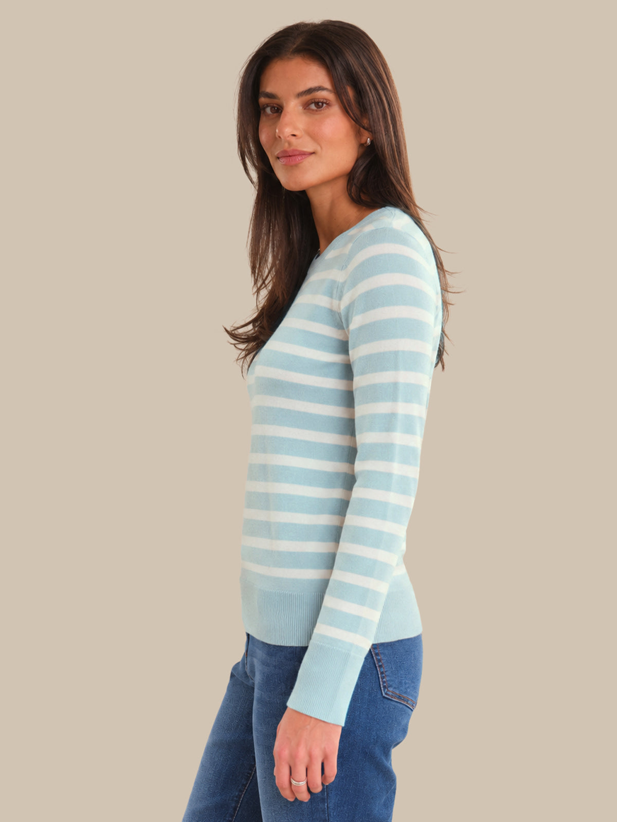 Woman wearing a light blue and white striped sweater against a beige background