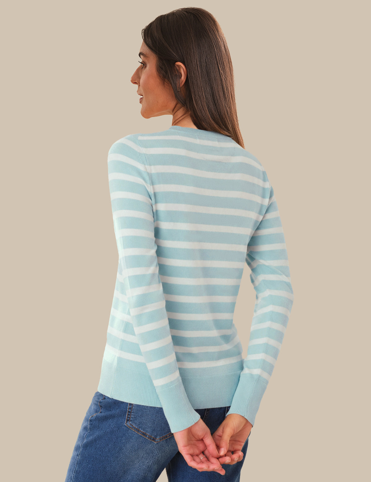 Woman wearing a light blue and white striped sweater against a beige background
