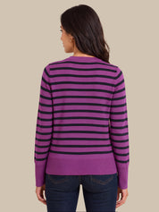 A woman shown from the back wearing a purple and black horizontally striped long-sleeve sweater, paired with dark blue jeans, against a solid beige background.