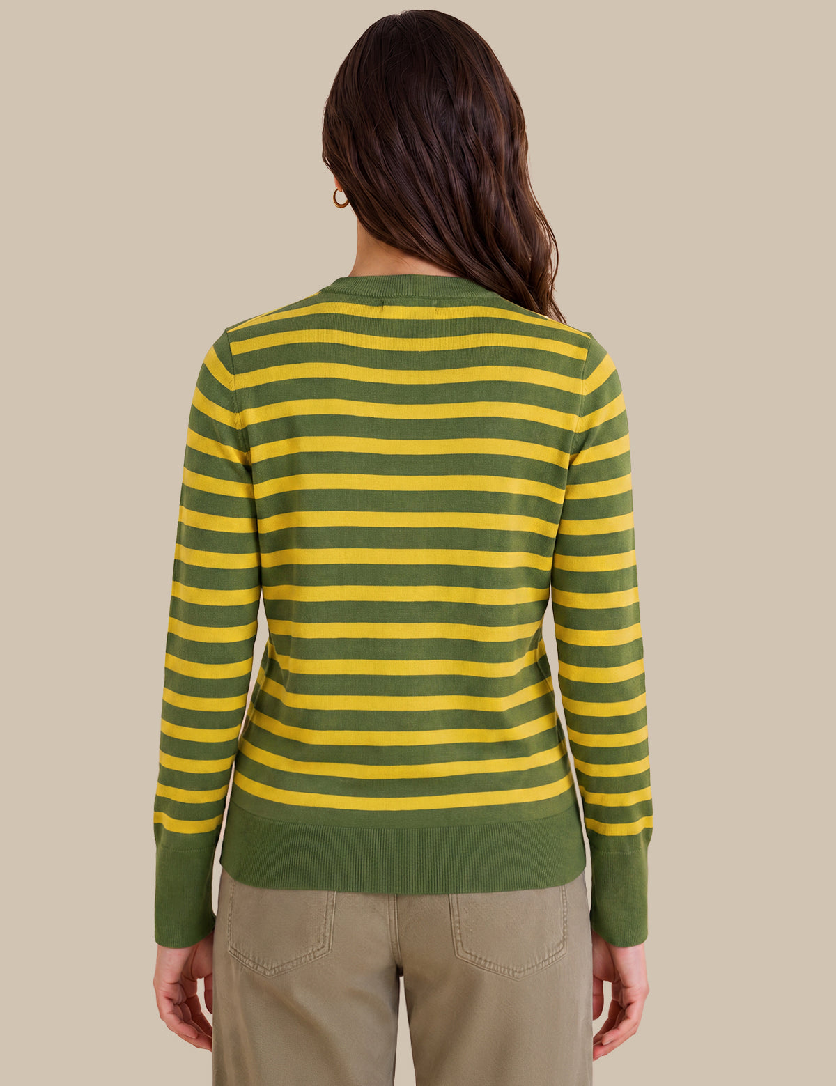 A woman viewed from the back wearing a green and yellow horizontally striped long-sleeve knit top with olive green ribbed cuffs, collar, and hem, paired with khaki pants, against a solid beige background.