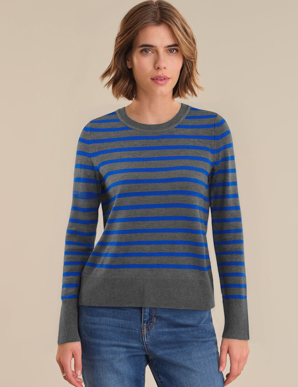 Woman wearing a blue and gray striped sweater with a beige background