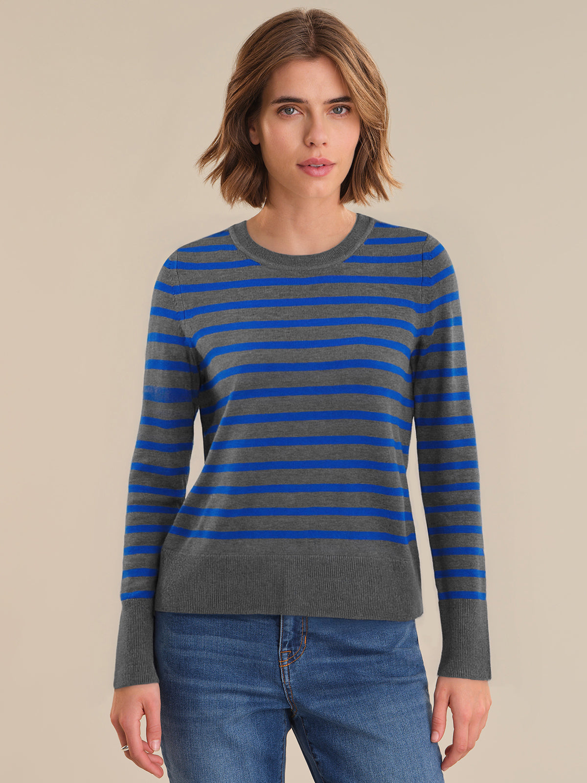 Woman wearing a blue and gray striped sweater with a beige background