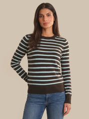 Woman wearing a striped sweater and jeans against a beige background
