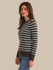 Woman wearing a brown and light blue striped sweater on a beige background