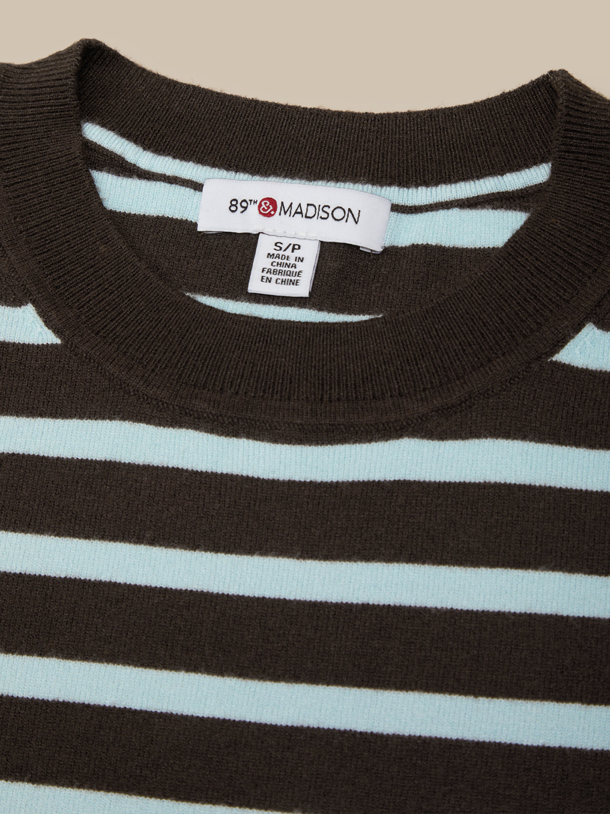 Close-up of a striped shirt with a brand label on a beige background