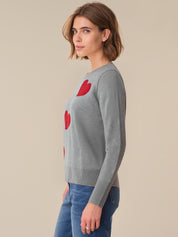 Woman wearing a gray sweater with red heart patterns on a beige background