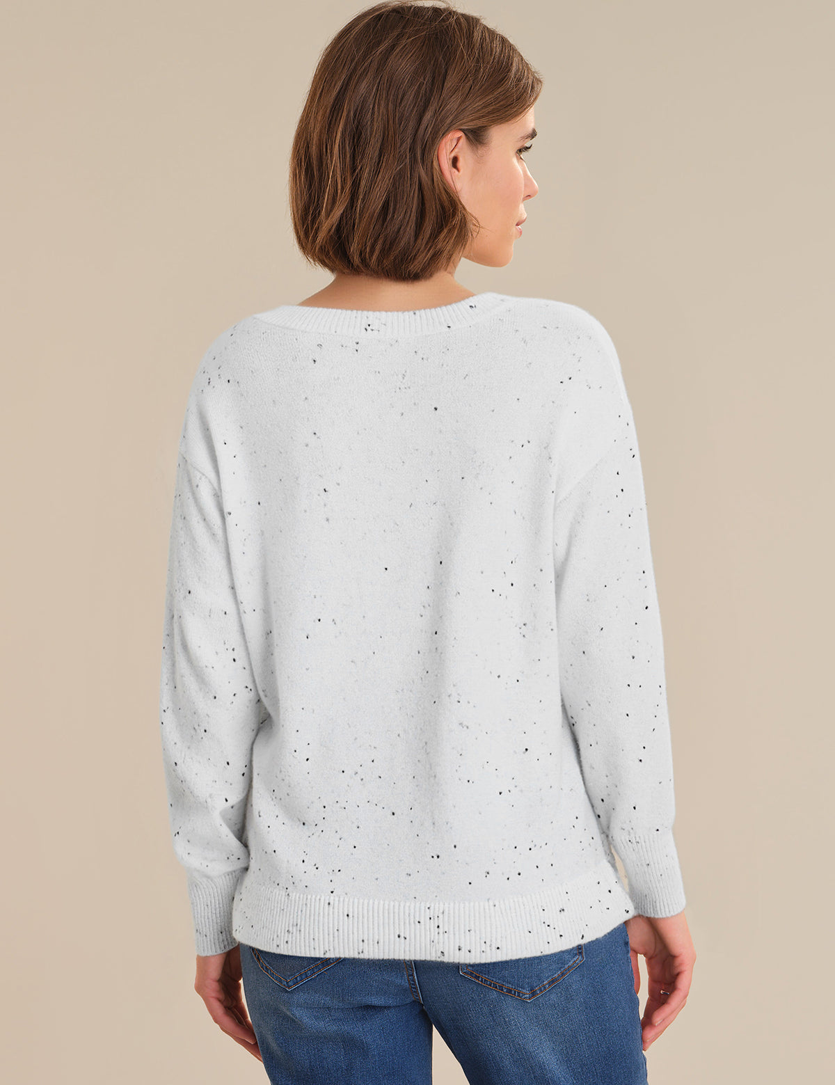 Woman wearing a light gray sweater with subtle pattern on a beige background