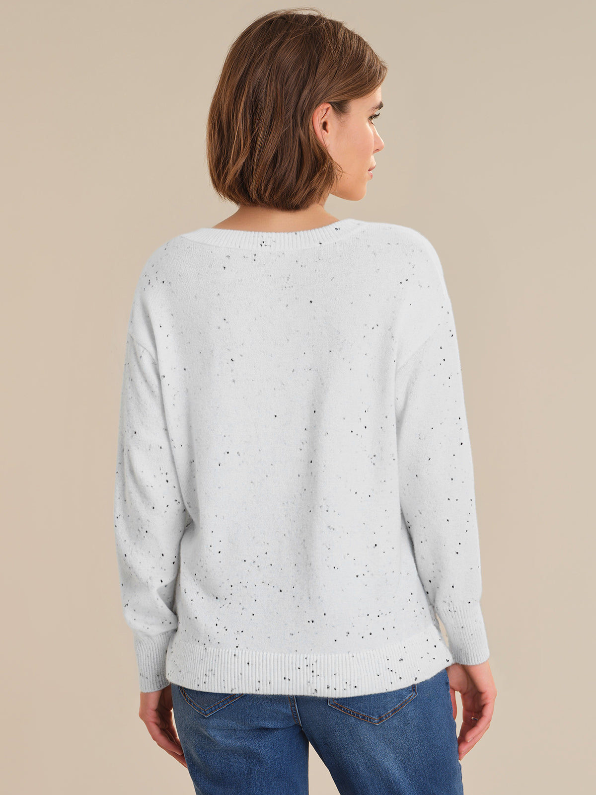 Woman wearing a light gray sweater with subtle pattern on a beige background