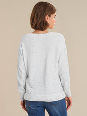 Woman wearing a light gray sweater with subtle pattern on a beige background