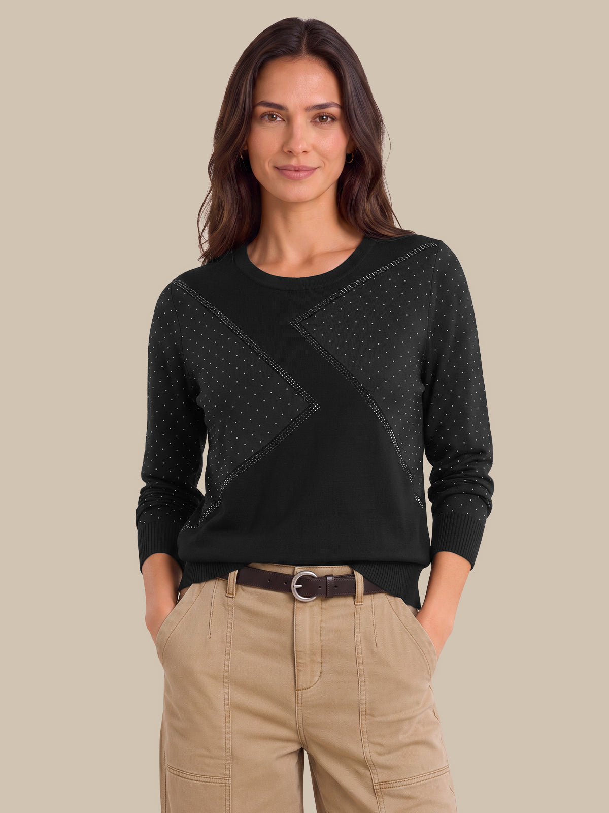 A woman modeling a black long-sleeve knit sweater with textured geometric panel details on the chest, paired with beige cargo pants, against a solid beige background.