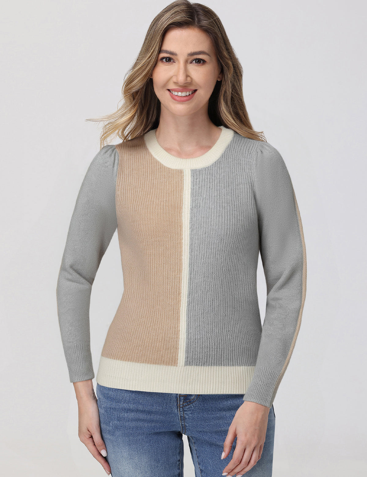 Woman wearing a gray and beige sweater with blue jeans on a white background
