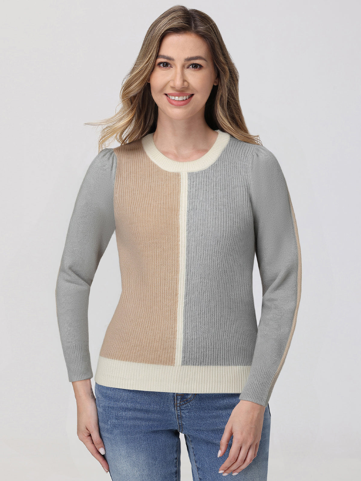 Woman wearing a gray and beige sweater with blue jeans on a white background