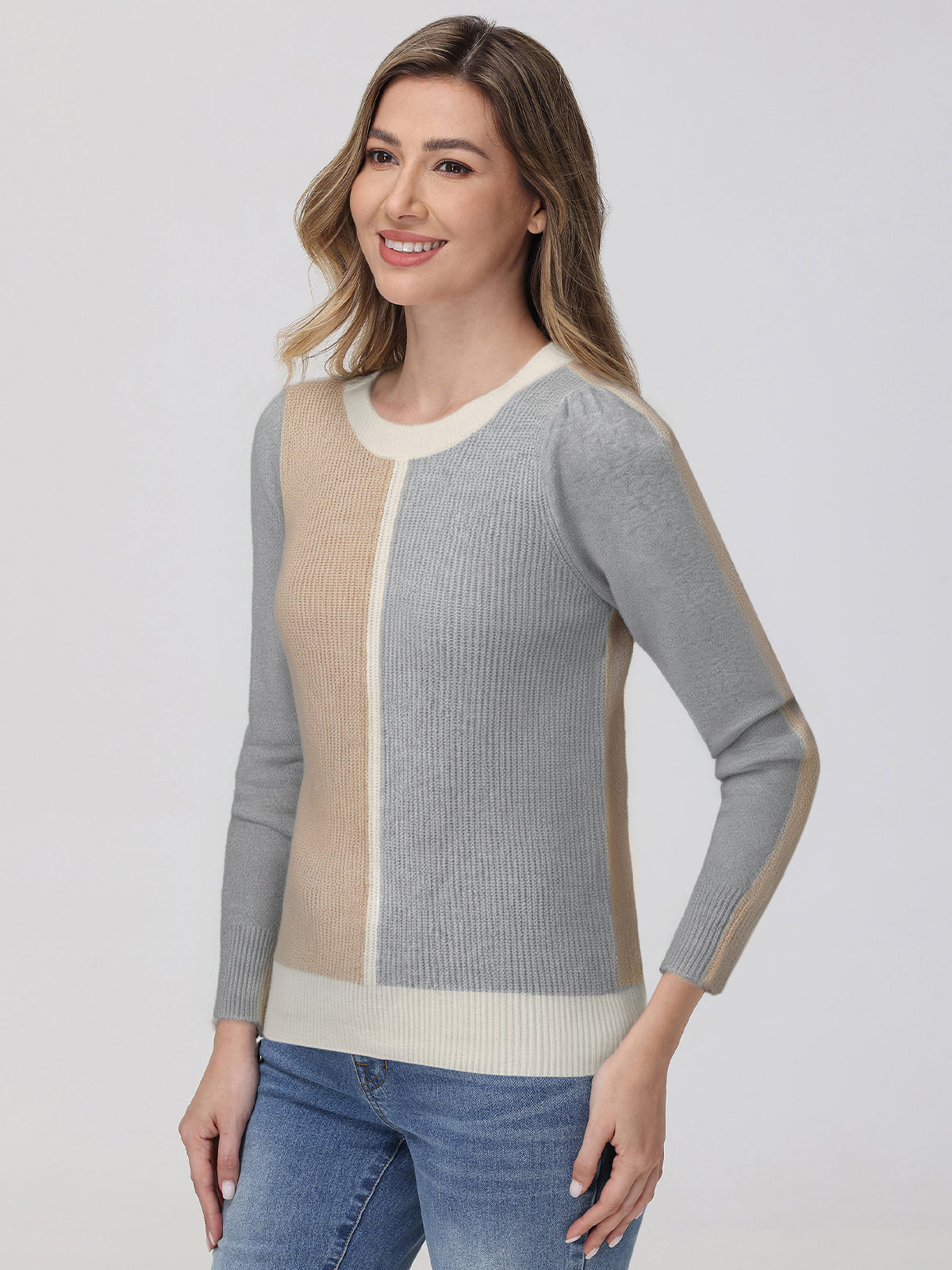 Woman wearing a gray and beige sweater with blue jeans on a white background