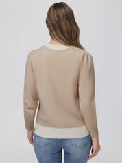Woman wearing a beige sweater and blue jeans on a white background