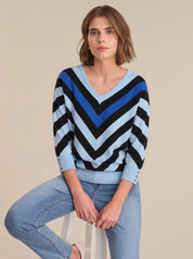 Woman wearing a blue and black striped sweater with light blue jeans on a beige background