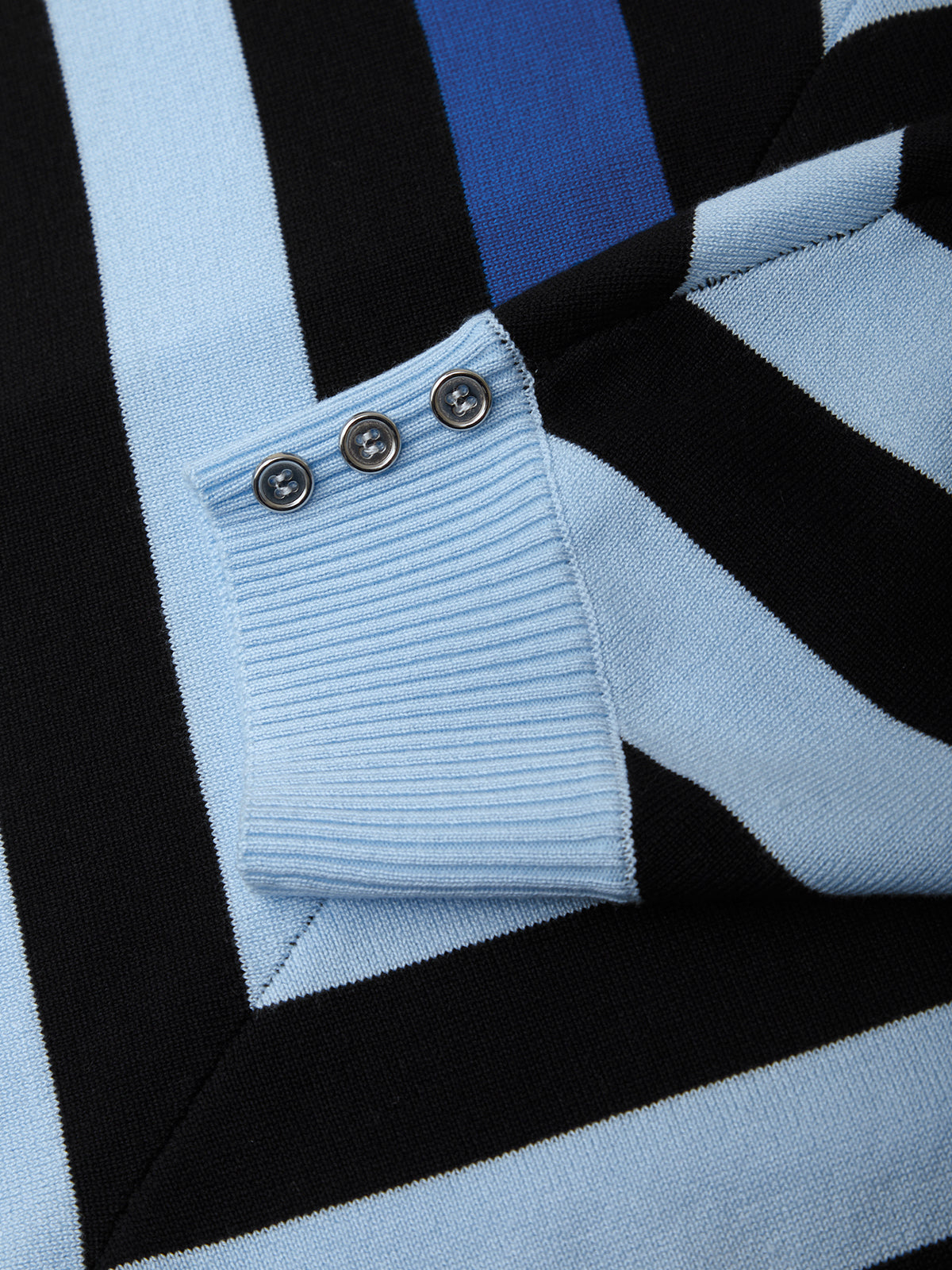 Close-up of a light blue sweater with black and white stripes and button details.