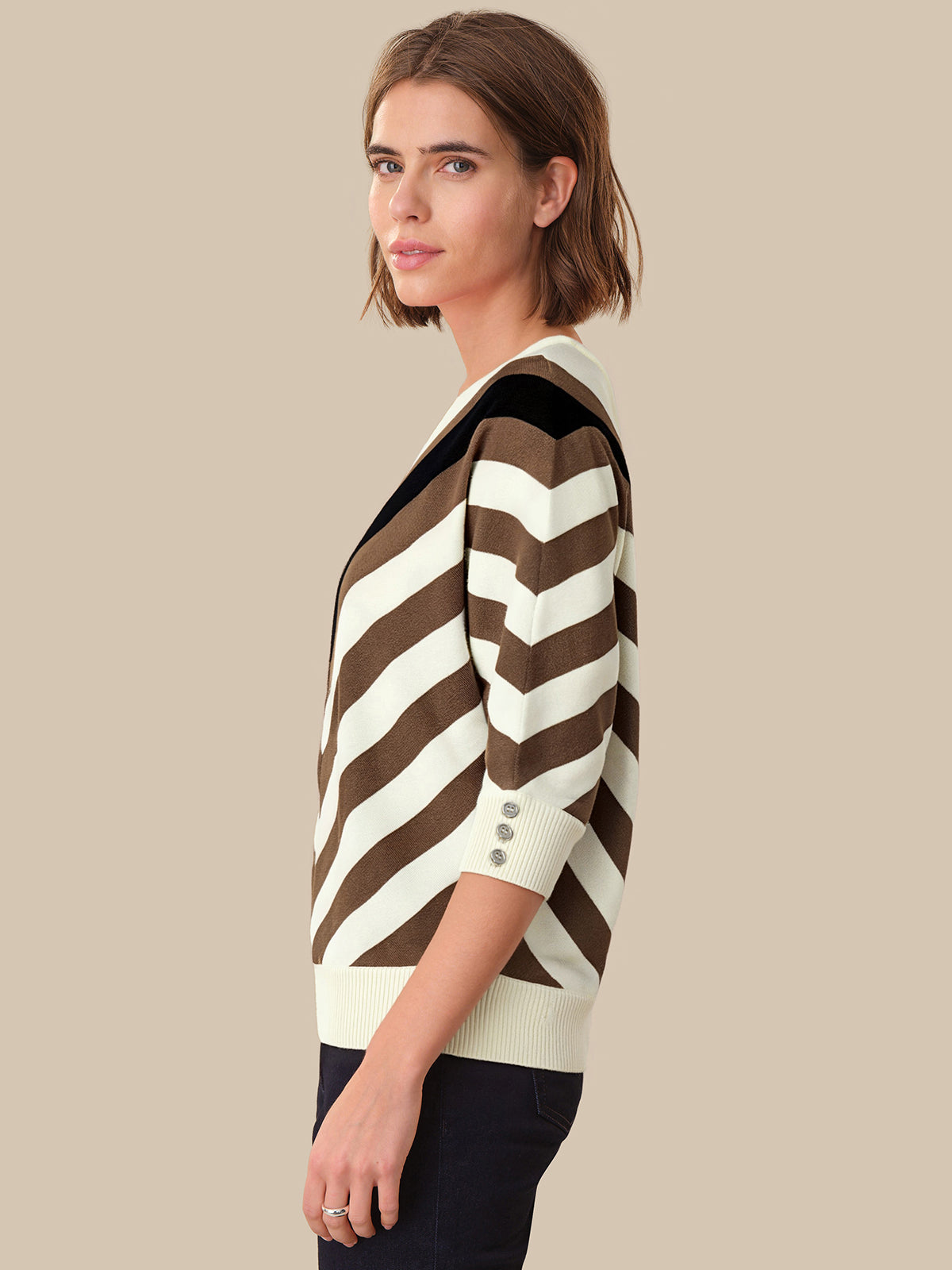 Woman wearing a brown and white striped sweater on a beige background