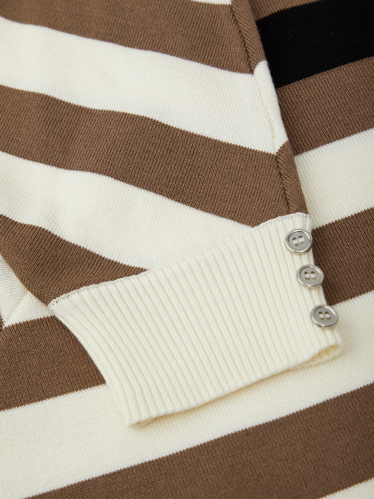 Close-up of a brown and white striped sweater with button details.