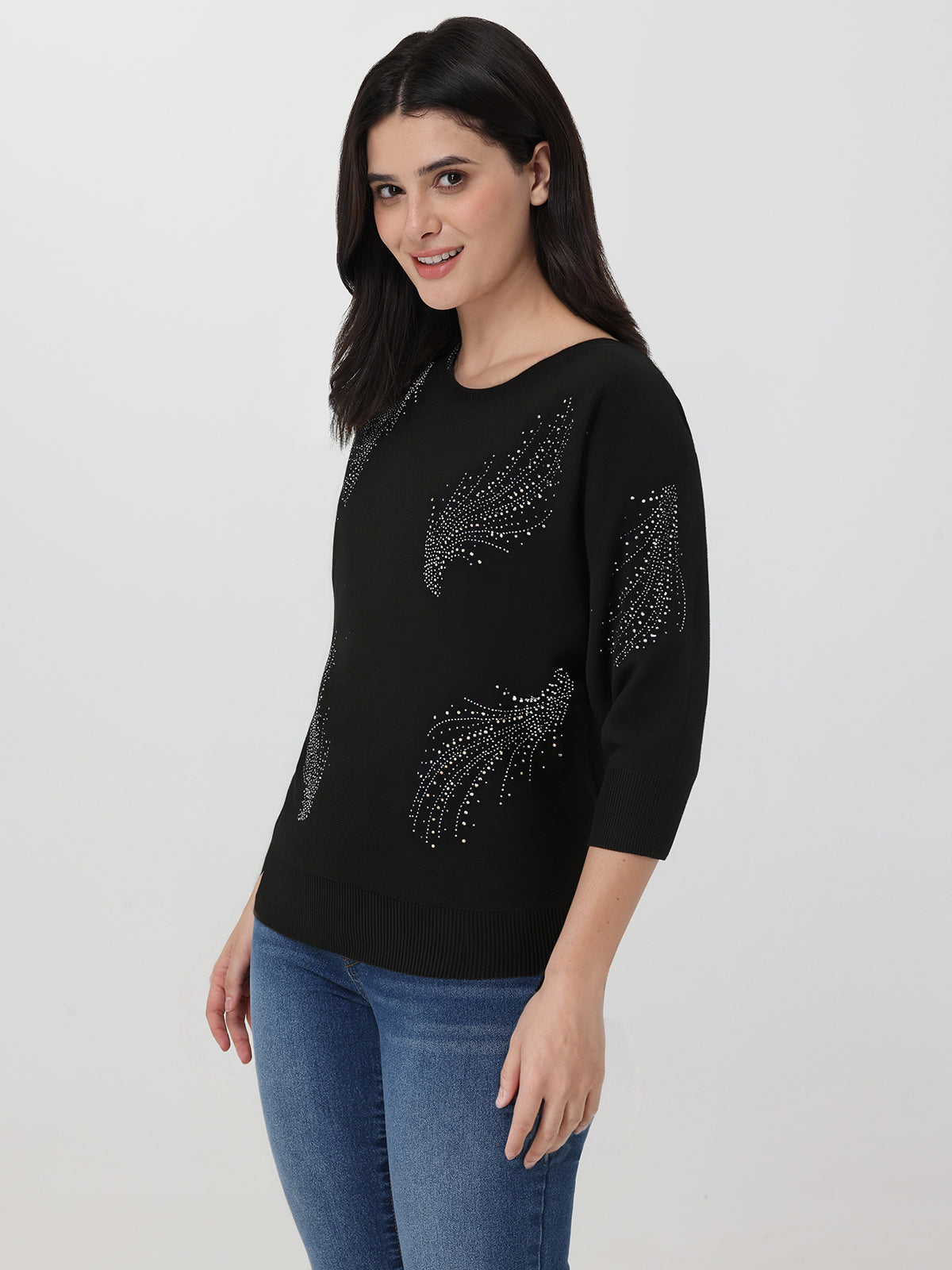 Woman wearing a black sweater with floral embellishments on a white background