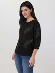 Woman wearing a black sweater with floral embellishments on a white background