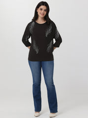 Woman wearing a black sweater with feather pattern and blue jeans on a white background
