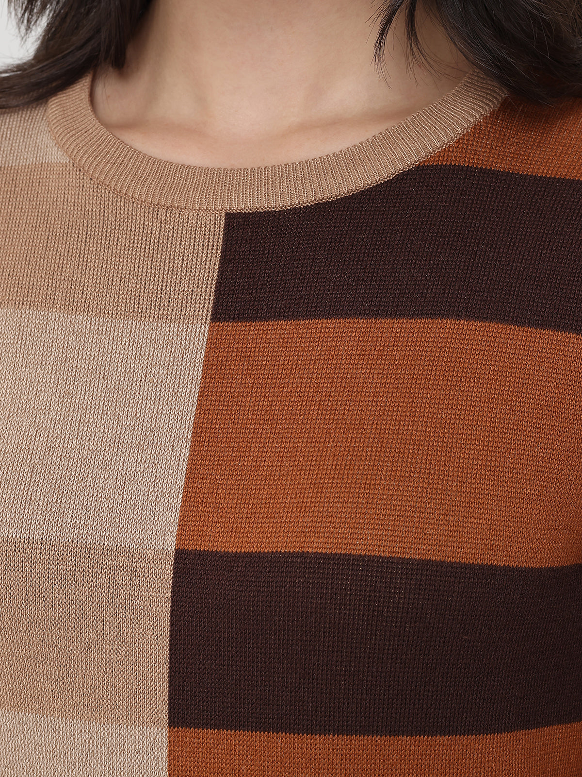Close-up of a person wearing a sweater with brown and beige color block design.