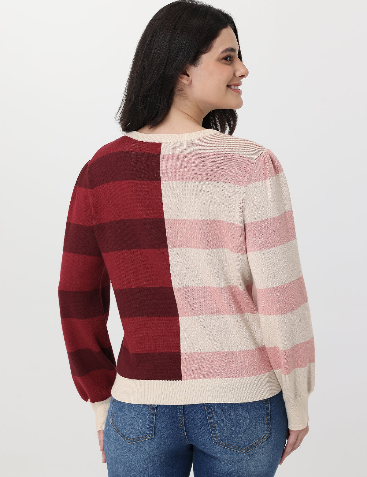 Woman wearing a checkered sweater with red, pink, and white stripes on a plain background