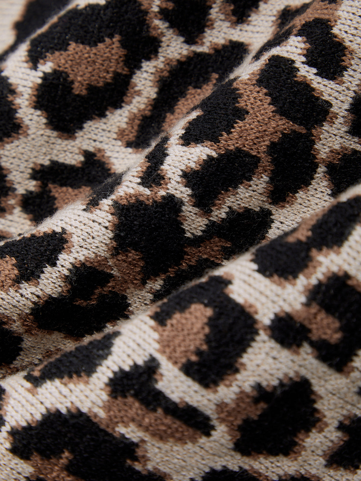 Close-up of a leopard print fabric with brown and black spots.