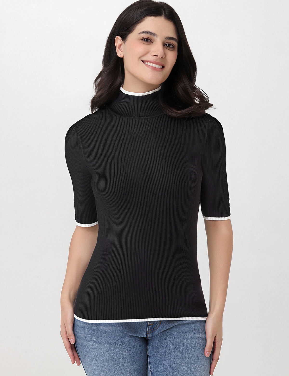 Woman wearing a black ribbed turtleneck sweater with a white collar on a light gray background