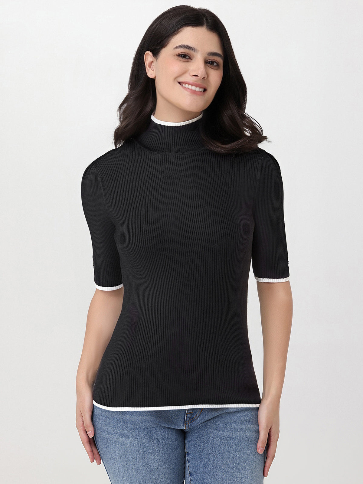 Woman wearing a black ribbed turtleneck sweater with a white collar on a light gray background