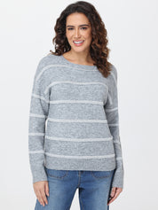 Woman wearing a gray striped sweater and blue jeans on a white background