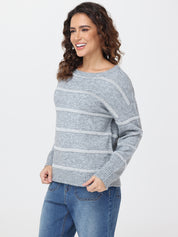 Woman wearing a gray sweater with white stripes and blue jeans on a white background
