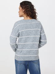 Person wearing a gray striped sweater and blue jeans on a white background