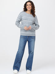 Woman wearing a gray striped sweater and blue jeans on a white background