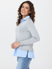 Woman wearing a gray sweater over a blue and white striped shirt on a white background