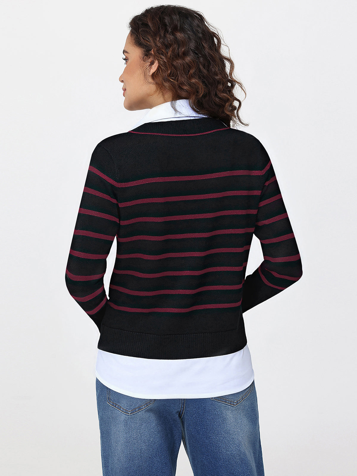 Woman wearing a black and red striped sweater over a white shirt with blue jeans on a white background