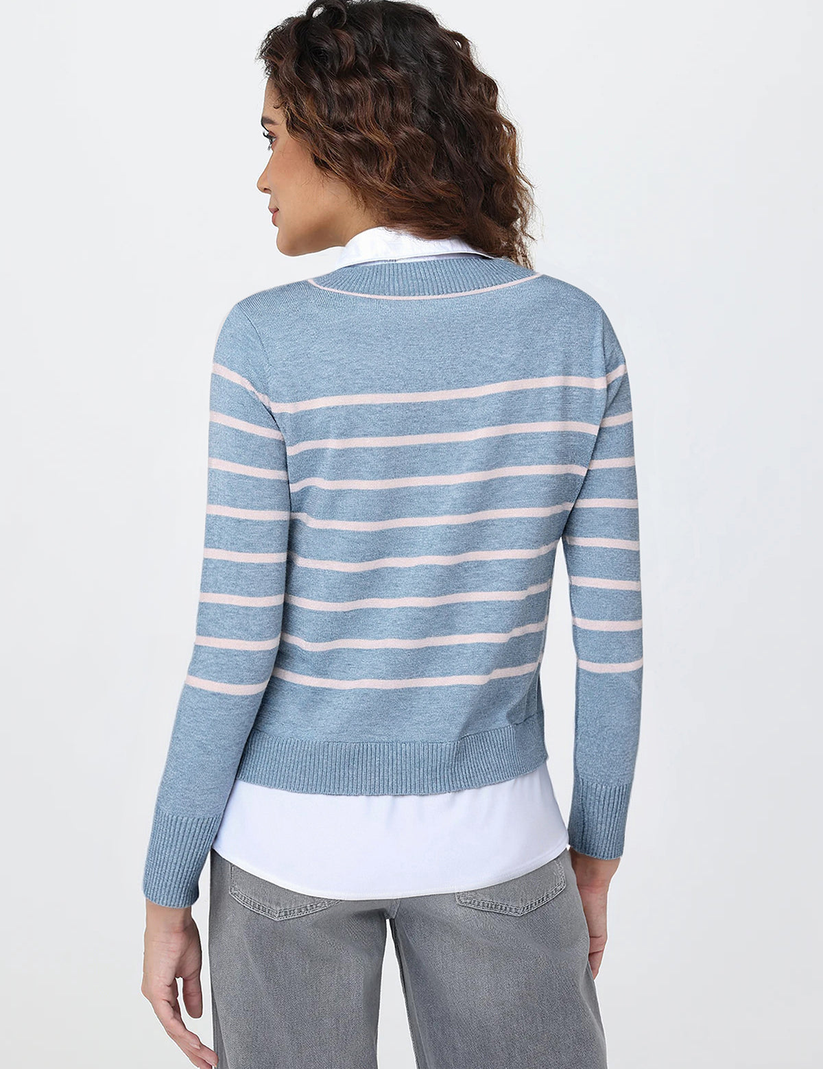 Woman wearing a blue and white striped sweater on a plain background